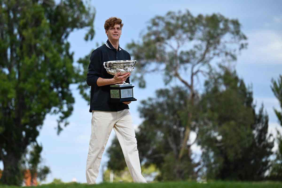 Jannik Sinner cammina a Melbourne Park con il trofeo