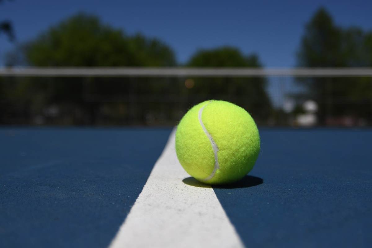 Pallina da tennis su un campo in cemento.