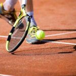 giocatore tennis raccoglie la pallina con la racchetta